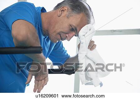Man wiping forehead on exercise machine View Large Photo Image Stock Image - Man wiping forehead on exercise machine. Fotosearch