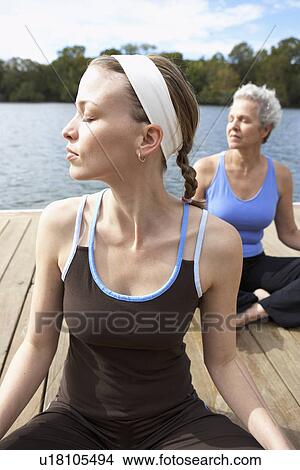Two women sitting crossed legs on deck View Large Photo Image Picture - Two women sitting crossed legs on deck. Fotosearch