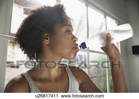 Stock Image - Young woman drinking water. Fotosearch