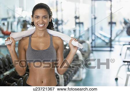 Young woman holding towel in gym (portrait) View Large Photo Image Stock Photo - Young woman holding towel in gym (portrait). Fotosearch