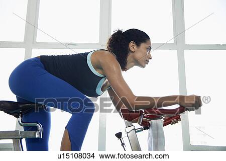 Young woman indoor cycling (low angle view) View Large Photo Image Picture - Young woman indoor cycling (low angle view). Fotosearch