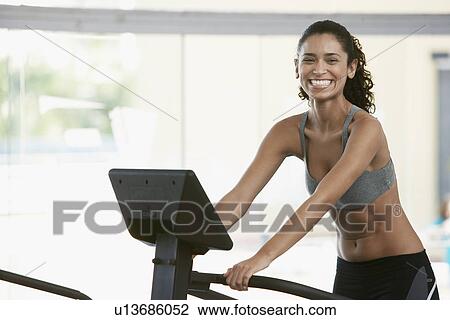 Stock Image - Young woman on step machine. Fotosearch
