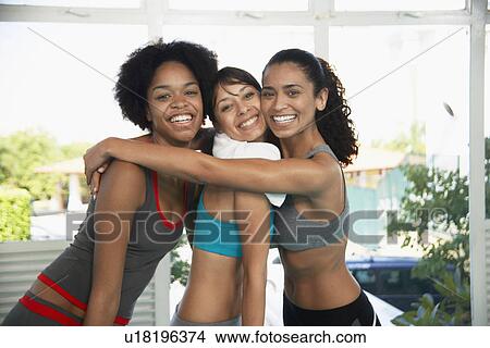 Picture - Young women in sports clothing hugging (portrait). Fotosearch