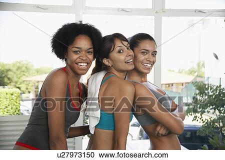 Stock Image - Young women in sports clothing hugging (portrait). Fotosearch