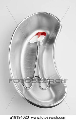 Stock Image - Medical scissors and blood stained swab in kidney dish. Fotosearch