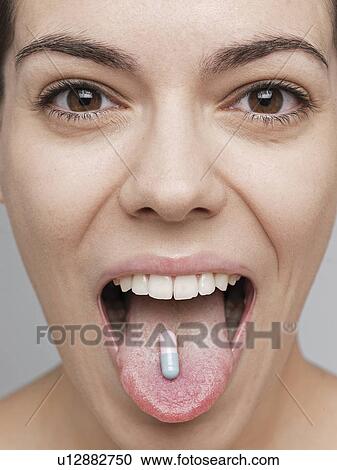 Stock Image - Vitamin pill on young woman's tongue. Fotosearch