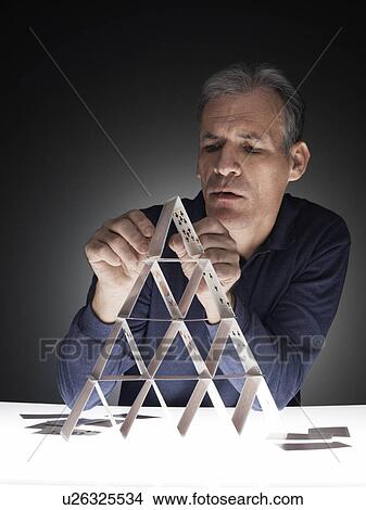 Picture - Mature man building house of cards. Fotosearch