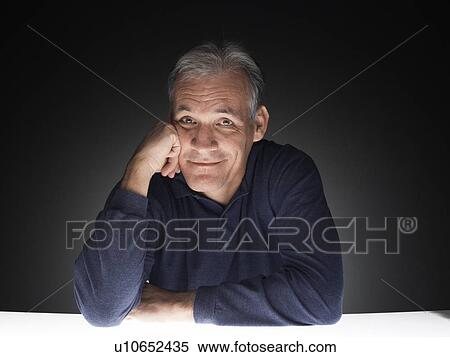 Stock Photography - Mature man leaning against his hand (portrait). Fotosearch