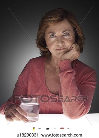 Stock Image - Mature woman taking medicine. Fotosearch
