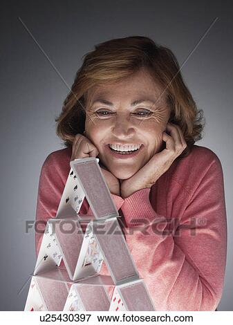 Woman looking at completed house of cards View Large Photo Image Stock Photo - Woman looking at completed house of cards. Fotosearch