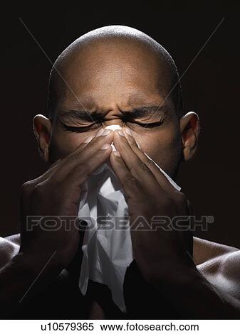 Stock Photography - Young man blowing nose. Fotosearch