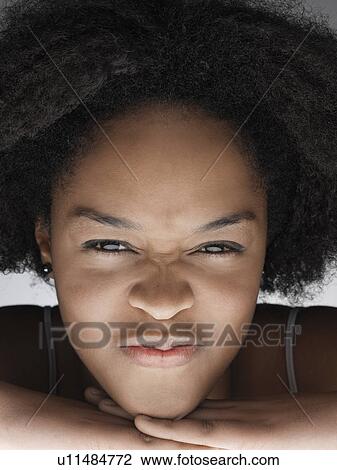 Stock Image - Young woman grimacing (portrait). Fotosearch