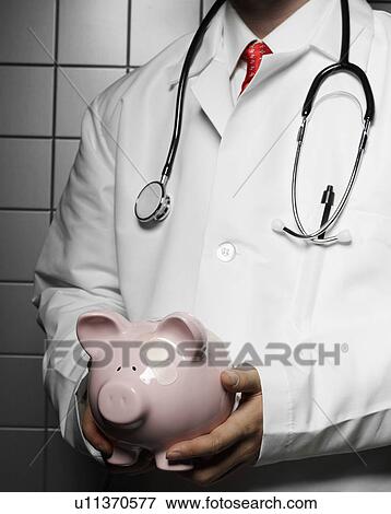 Stock Photo - Doctor Holding Piggy Bank. Fotosearch