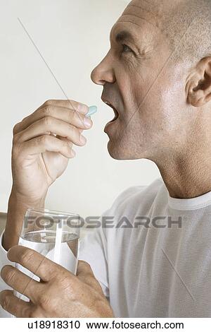 Stock Image - Mature man having a vitamin pill. Fotosearch