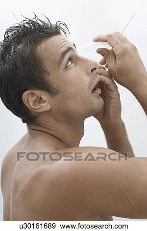 Mid adult man putting in eye drops View Large Photo Image Stock Photo - Mid adult man putting in eye drops. Fotosearch