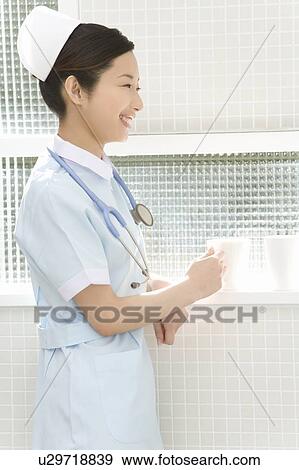 Nurse holding a mug, smiling, side view View Large Photo Image Stock Photo - Nurse holding a mug, smiling, side view. Fotosearch