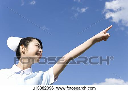 Nurse smiling and pointing up under the blue sky, low angle view View Large Photo Image Stock Photograph - Nurse smiling and pointing up under the blue sky, low angle view. Fotosearch