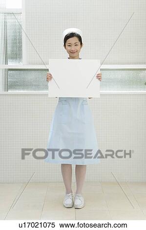Portrait of a nurse holding a blank board, smiling and looking at camera, front view View Large Photo Image Stock Photography - Portrait of a nurse holding a blank board, smiling and looking at camera, front view. Fotosearch