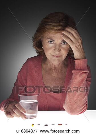 Stock Photo - Woman with headache taking pills. Fotosearch