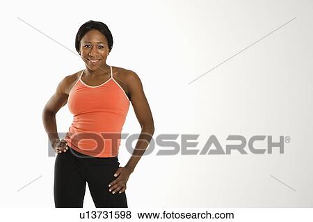 Stock Photo - African American young adult woman in athletic wear smiling at viewer with hands on hips.. Fotosearch