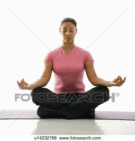 Stock Photo - Mid adult multiethnic woman sitting in lotus position on exercise mat with eyes closed and legs crossed.. Fotosearch