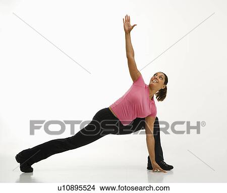 Picture - Mid adult multiethnic woman wearing exercise clothing holding yoga pose and smiling.. Fotosearch