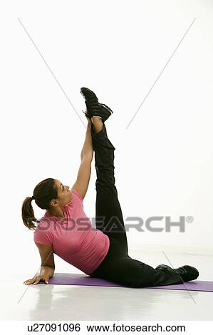 Stock Photograph - Mid adult multiethnic woman wearing exercise clothing holding yoga pose and stretching.. Fotosearch