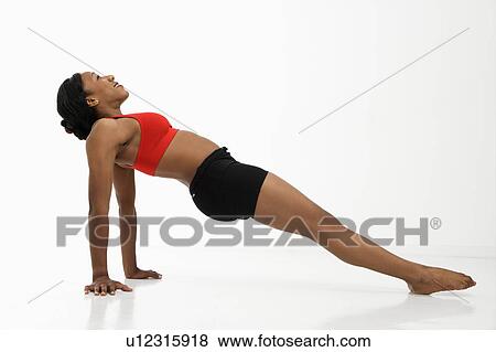 Stock Photo - Profile of African American young adult woman exercising in strength training position.. Fotosearch