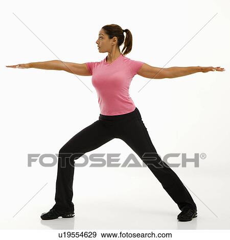 Stock Photo - Side view of mid adult multiethnic woman wearing exercise clothing standing in yoga warrior pose.. Fotosearch