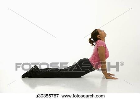 Stock Photo - Side view of mid adult multiethnic woman wearing exercise clothing holding cobra yoga pose.. Fotosearch