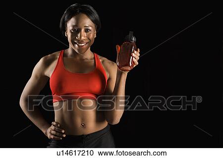 Smiling African American young adult woman holding water bottle with hand on hip. View Large Photo Image Stock Image - Smiling African American young adult woman holding water bottle with hand on hip.. Fotosearch