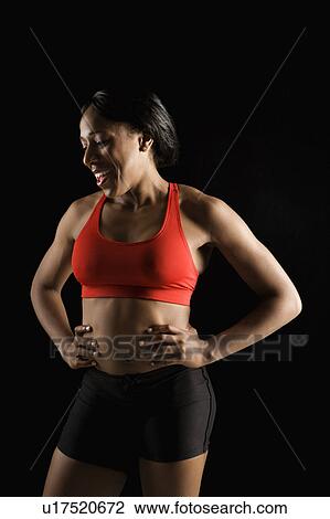 Stock Image - Smiling African American young adult woman in athletic apparel with hands on hips.. Fotosearch