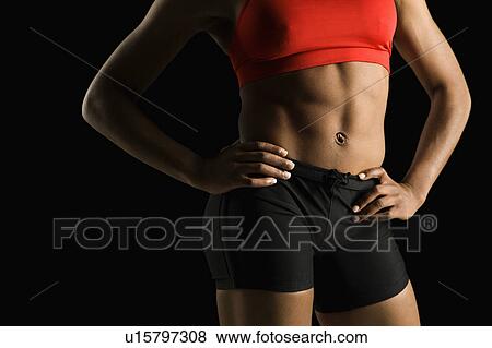 Stock Photo - Torso of muscular African American woman wearing athletic apparel with hands on hips.. Fotosearch