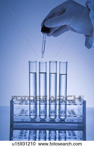 Hand holding dropper over test tubes. View Large Photo Image Stock Image - Hand holding dropper over test tubes.. Fotosearch