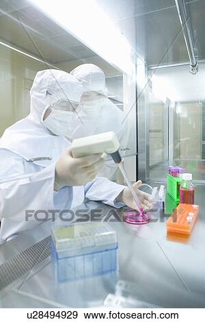 Stock Photo - Mature scientist man injecting liquid into a test tube in laboratory, young woman looking, side view,. Fotosearch