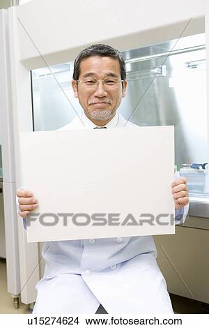Portrait of a mature scientist man holding a white board, front view View Large Photo Image Picture - Portrait of a mature scientist man holding a white board, front view. Fotosearch