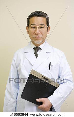 Picture - Portrait of a mature scientist man holding a file, front view. Fotosearch