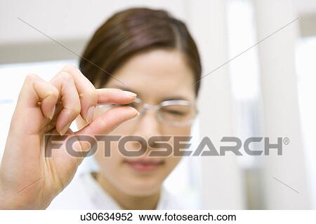 Stock Image - Portrait of a young scientist woman making hand gesture, front view, close up, Differential Focus. Fotosearch