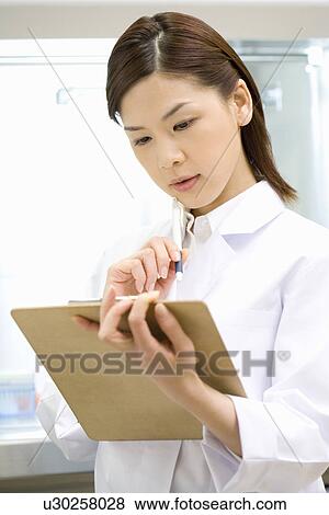 Stock Photo - Young scientist woman holding a document in laboratory, side view. Fotosearch