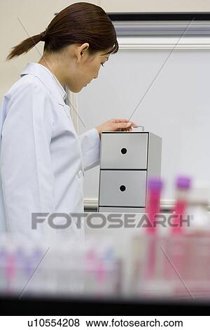 Stock Photo - Young scientist woman in laboratory, test tubes in foreground, Differential Focus. Fotosearch