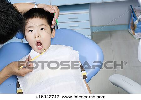Stock Image - Close-up of a dentist examining a boy's teeth. Fotosearch