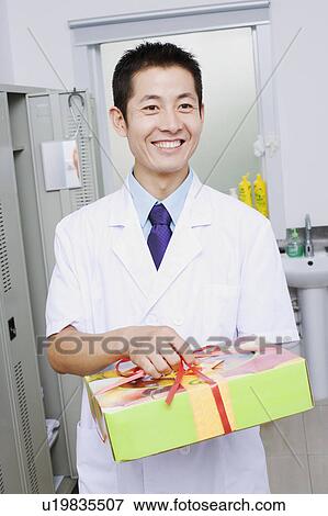 Close-up of a doctor holding a gift View Large Photo Image Stock Photo - Close-up of a doctor holding a gift. Fotosearch