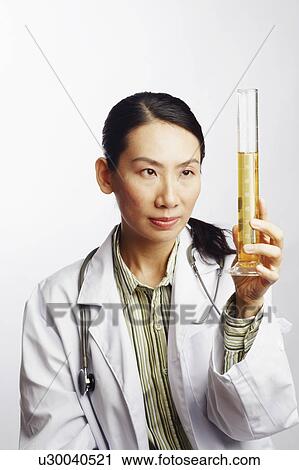 Stock Image - Close-up of a female doctor holding a graduated cylinder. Fotosearch