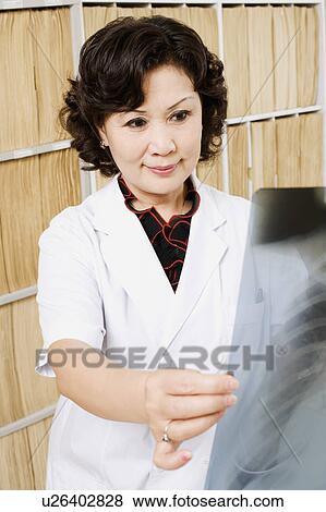 Stock Photo - Close-up of a female doctor looking an X-Ray image. Fotosearch