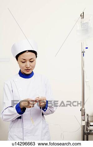 Stock Image - Close-up of a female nurse holding an iv drip. Fotosearch
