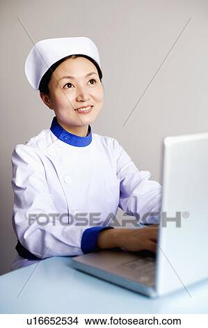 Picture - Close-up of a female nurse working on a laptop. Fotosearch