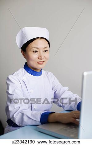 Stock Image - Close-up of a female nurse working on a laptop. Fotosearch