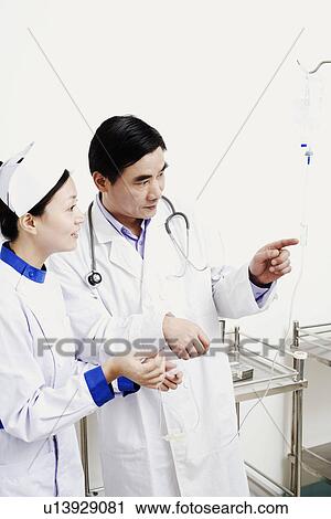 Stock Image - Close-up of a male doctor and a female nurse looking at an iv drip. Fotosearch