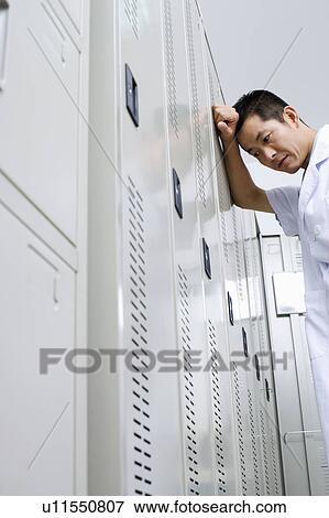 Stock Photo - Low angle view of a doctor leaning against a locker. Fotosearch