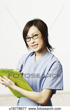 Stock Photo - Portrait of a female doctor holding a clip board and a pen. Fotosearch